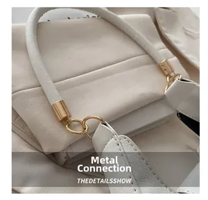 Close-up of golden hardware connection on minimalist white underarm crescent bag