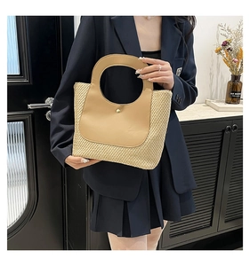 Close-up of handmade straw tote featuring contrast leather panel and gold metal buckle