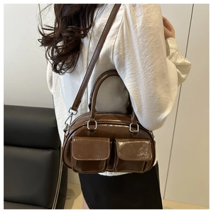 Detail of dark brown glossy crossbody bag featuring dual front pockets and silver hardware