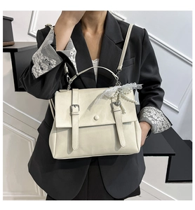 Sac messager vintage crème porté en sac à dos par un mannequin en blazer