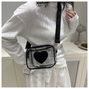 Vista dettagliata di una borsa a tracolla trasparente con cuore nero indossata da una modella