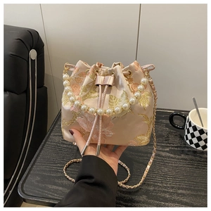 Detail of pink satin bucket bag with gold floral embroidery and large pearl handle