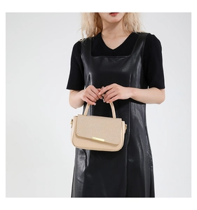 Elegante borsa a mano beige in patchwork strutturato tenuta da una modella in nero