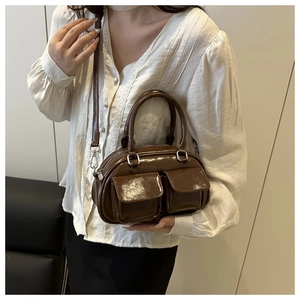 Detail of dark brown glossy bowling bag featuring dual front pockets and silver buckles