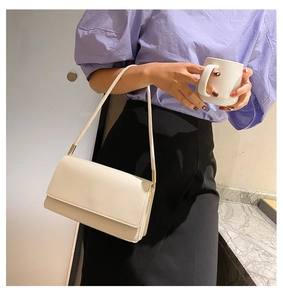 Minimalist cream shoulder bag with leather texture shown worn by a model in detail