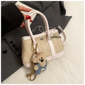 Detail of straw woven tote with white leather trim and cute plush bear charm