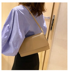 Detail of minimalist khaki leather underarm bag showing rectangular flap and stitching