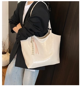Detail of beige oil wax leather tote bag with embossed logo and woven strap decoration