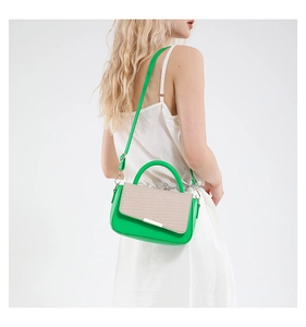 Vista laterale di una borsa a mano verde indossata da una modella in abito bianco