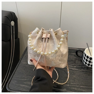 Detail of embroidered bucket bag with pearl handle and golden chain strap for women