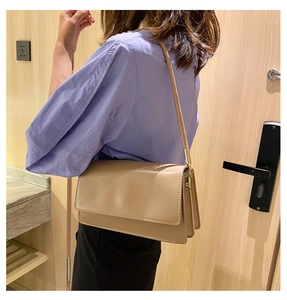Detail view of a beige leather shoulder bag with a three-layer gusset design
