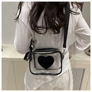Detail of transparent crossbody bag featuring a black heart patch and nylon strap