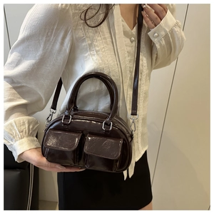 Detail of dark brown patent leather baguette bag with dual front flap pockets and silver hardware