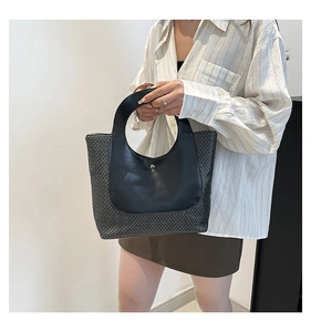 Detail of vintage contrast woven tote bag with smooth leather patch and metal buckle decoration
