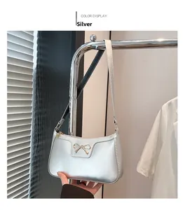 Détail d'un sac sous le bras croissant argenté avec un fermoir nœud doré élégant