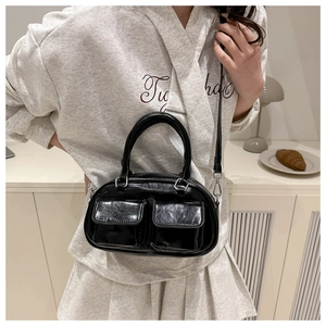 Close-up of a glossy black patent leather shoulder bag with two front square flap pockets