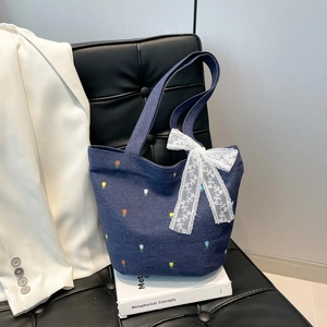 Denim tote bag with tulip embroidery and lace bow on a sophisticated studio background