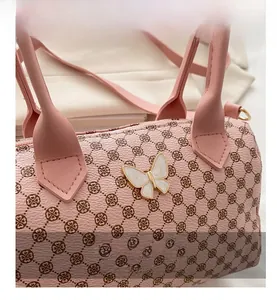 Detail of pink cylinder handbag with clover pattern and gold-rimmed butterfly ornament