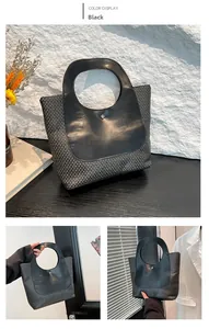 Detail of black straw tote bag featuring round leather handle and woven texture texture