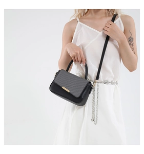 Elegante borsa a mano patchwork nera e grigia indossata da una modella in abito bianco