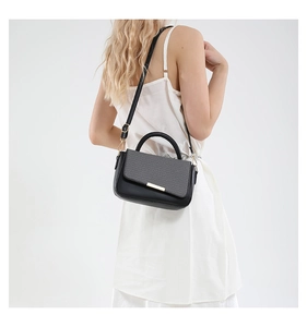 Elegante borsa a tracolla strutturata nera e grigia indossata da una modella in abito bianco
