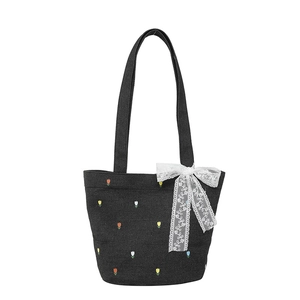 Denim tote bag with floral embroidery and white lace bow in a minimalist studio shot
