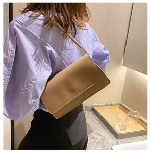 Detail of khaki leather shoulder bag showing fine stitching and gold metal buckle