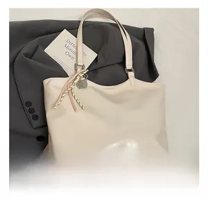 Detailed close-up of cream PU leather tote bag featuring an embossed brand logo and strap