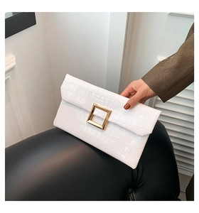 Detail of white crocodile embossed leather clutch with square gold metal buckle