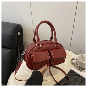 Detail of dark red glossy patent leather handbag with dual front pockets and silver hardware