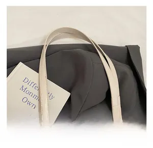 Detail of minimalist cream tote bag with slim handles and silver square metal buckles