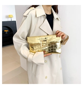 Macro detail of metallic gold crocodile embossed clutch bag with square metal buckle