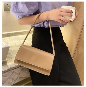 Minimalist beige leather shoulder bag with sleek flap and gold metal hardware detail