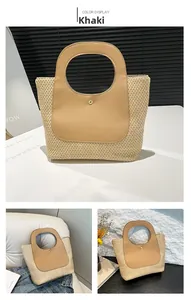 Close-up of contrast khaki leather handle on woven straw tote with golden metal button