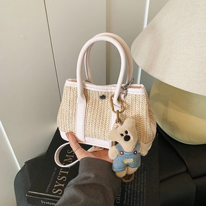 Large capacity straw handbag with pink leather trim and cute bear charm in warm light