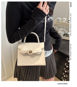 Detail of cream crossbody bag featuring a golden round lock and smooth leather texture