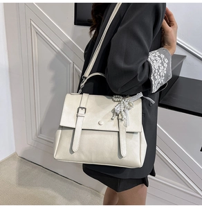 Mannequin présentant un sac à main vintage beige avec un détail de breloque en perles