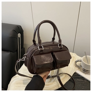 Detail of glossy brown leather handbag with two front pockets and dual carry straps