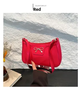 Détail du sac bandoulière croissant rouge avec nœud en métal doré et cuir brillant
