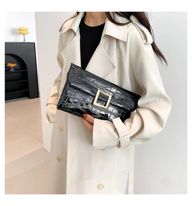 Detail shot of the black crocodile pattern leather clutch with elegant gold metal buckle