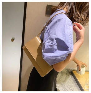 Chic khaki faux leather underarm bag worn by a model in a minimalist indoor setting