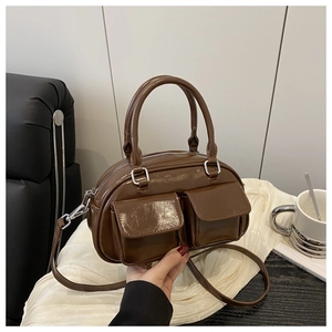Detail of glossy brown handbag featuring double front pockets and silver hardware finish