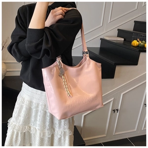 Detail of light pink tote bag with embossed logo and striped tassel accessory