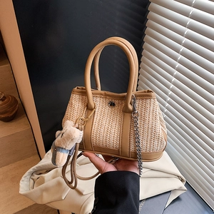 Straw handbag with leather trim and bear pendant shown in a warm, artistic lifestyle setting