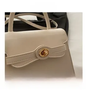 Close-up of beige handbag with golden twist-lock and decorative bow detail