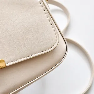 Primer plano detallado de las costuras finas y la piel texturizada de un bolso beige