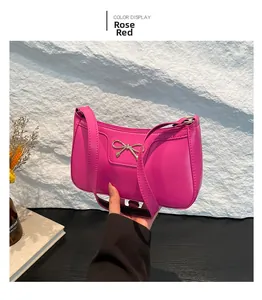 Détail du sac sous l'aisselle magenta avec nœud argenté et texture en cuir PU mat