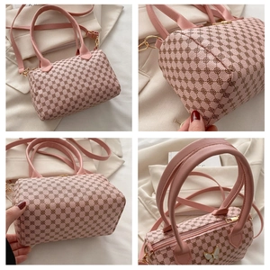 Detail view of pink Boston bag with vintage pattern, golden hardware and butterfly charm