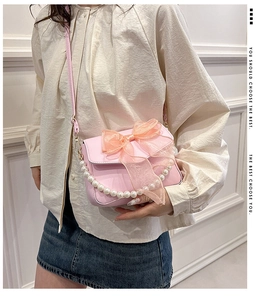 Detailaufnahme der rosa Umhängetasche mit Organzaschleife und Perlen griff am Model