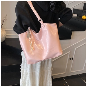 Detail of glossy pink tote bag with tennis racket charm and embossed brand logo